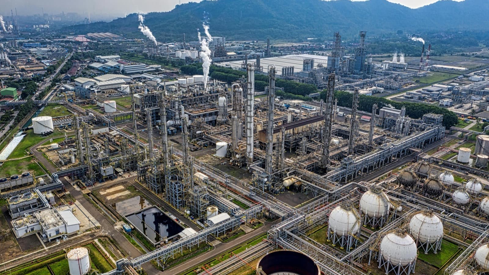 Aerial view of a refinery showing storage tanks, pipelines, and process units at dusk