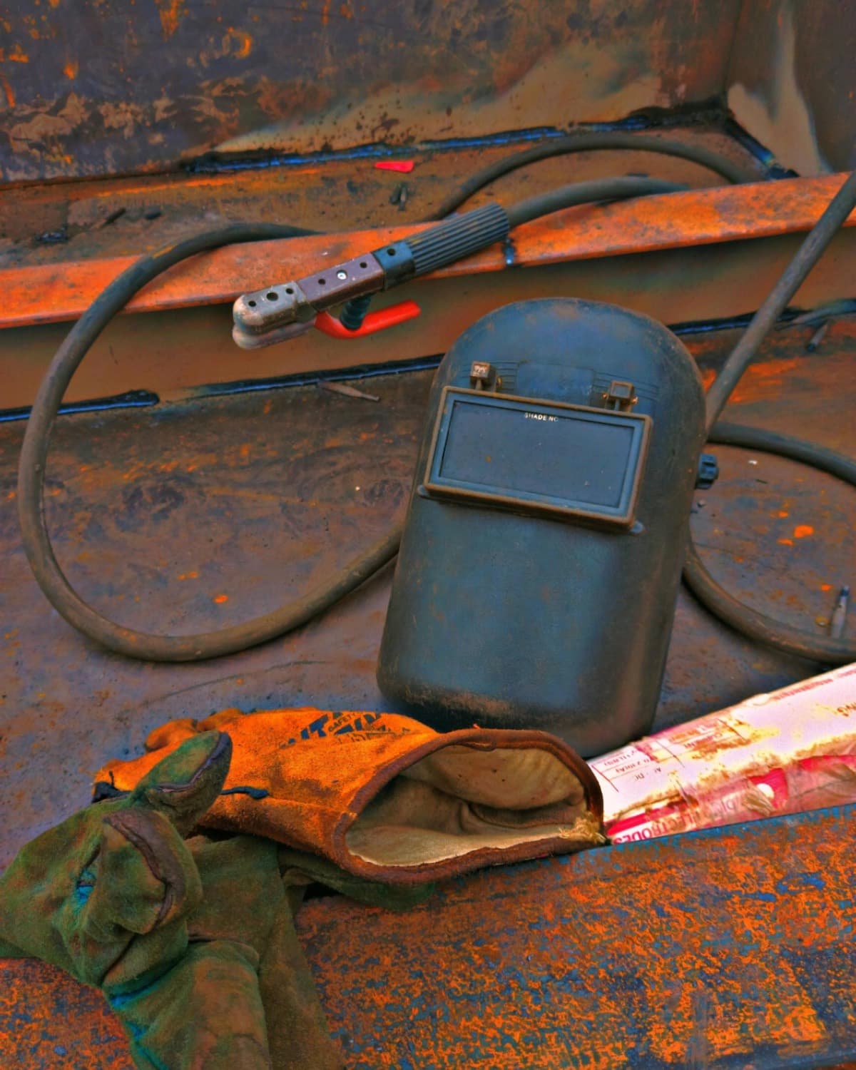 Close-up of welding helmet and protective gloves resting on industrial metalwork